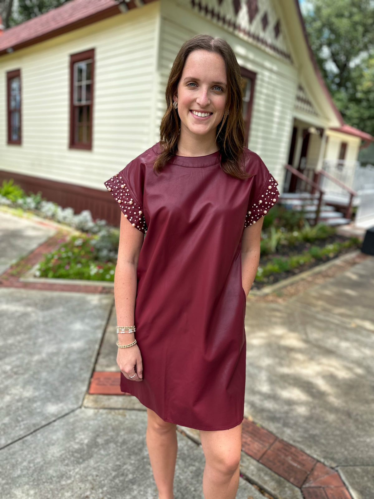 maroon leather style dress with pearl details on the sleeves 