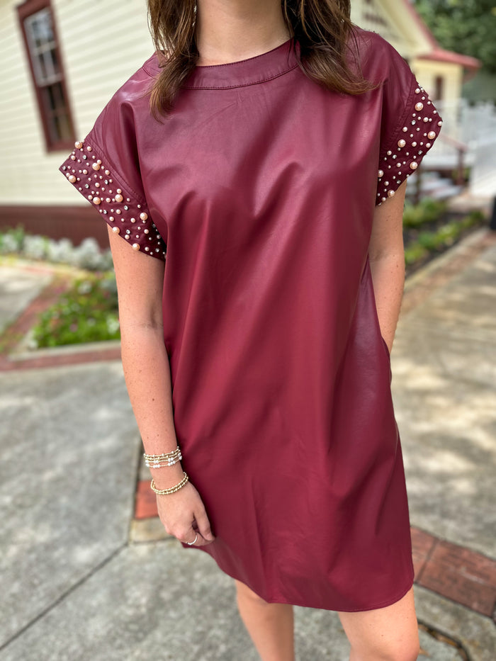 maroon leather style dress with pearl details on the sleeves 